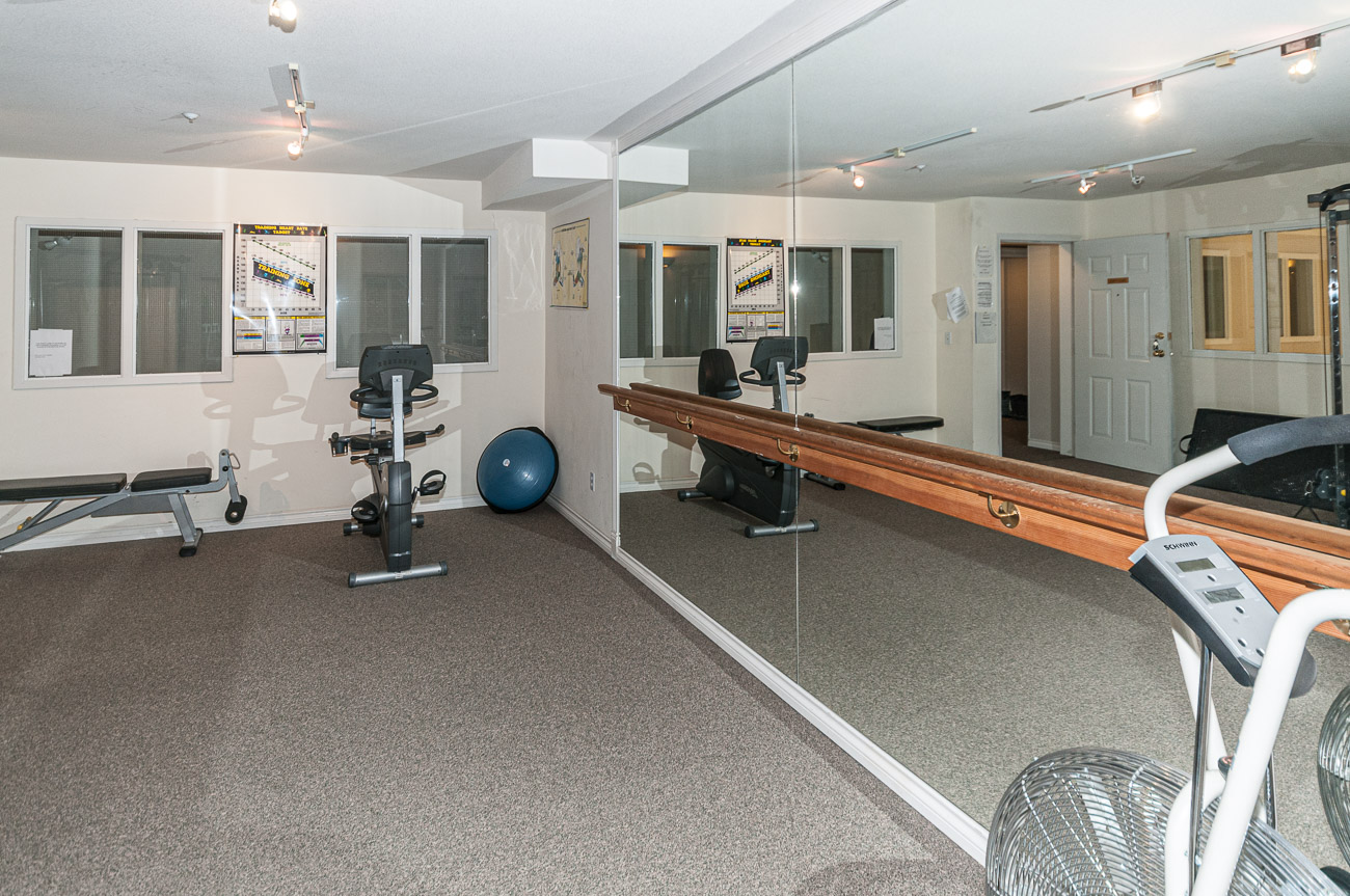 Bright exercise room with mirrored walls and cardio equipment. - 208-128 8th Street West, North Vancouver