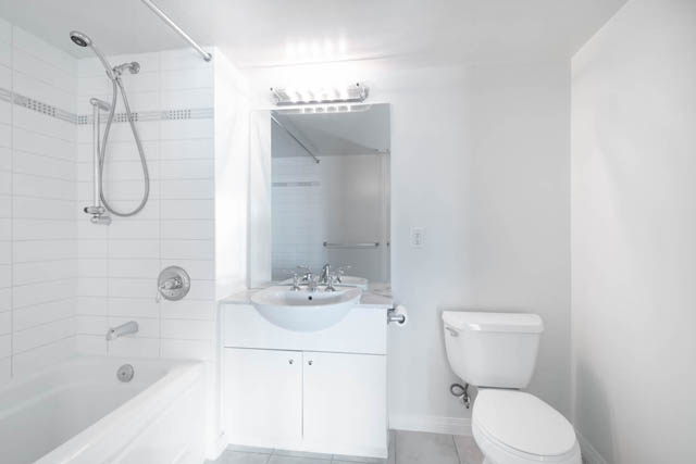 Bright bathroom with white tile shower and modern vanity sink. - 704-188 East Esplanade, North Vancouver