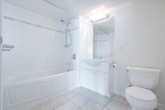 Spacious bathroom with white tile, modern sink, and a bathtub/shower combo. - 704-188 East Esplanade, North Vancouver