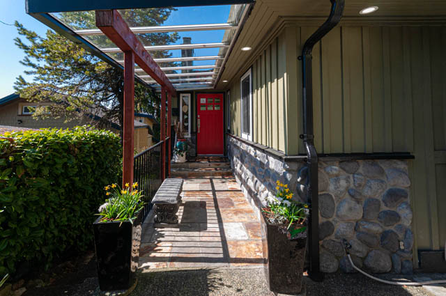 Cozy front porch with a red door, stone steps, and a covered patio. - 2128 Grand Blvd, North Vancouver