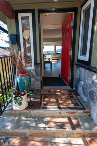 Cozy entryway with a red door and stone accents, leading to a bright living area with hardwood floors and a city view.
