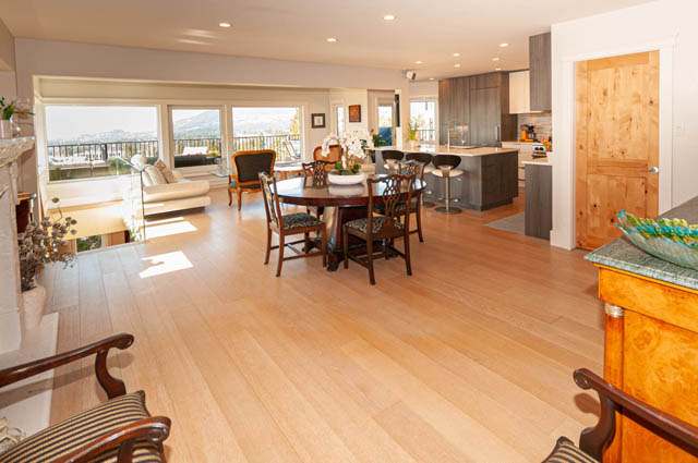 Spacious open-concept living room with hardwood floors, a large dining table, and a view of the city. - 2128 Grand Blvd, North Vancouver