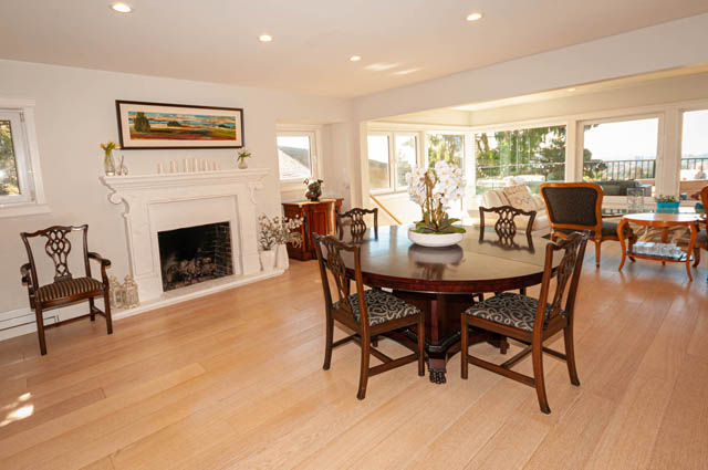 Spacious dining room with hardwood floors, large windows, and a cozy fireplace. - 2128 Grand Blvd, North Vancouver