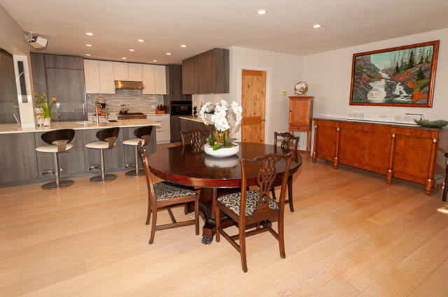 Spacious kitchen and dining area with hardwood floors, modern cabinetry, and a large painting of a waterfall. - 2128 Grand Blvd, North Vancouver