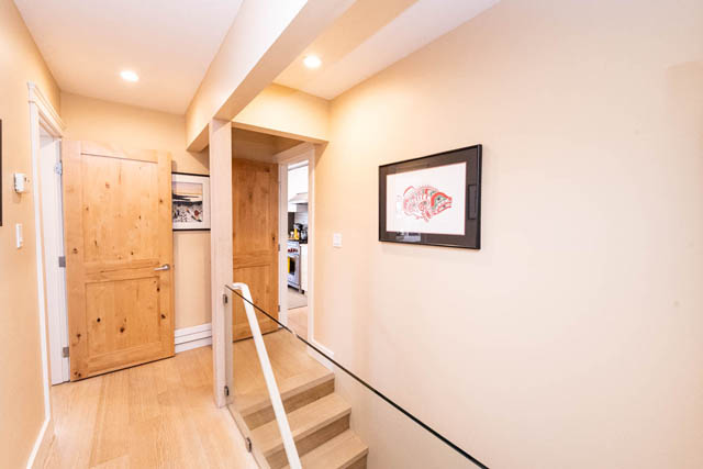Hallway with hardwood floors and rustic wooden doors leading to kitchen. - 2128 Grand Blvd, North Vancouver
