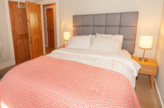 Spacious bedroom with a modern bed, patterned bedding, and wooden bedside tables. - 2128 Grand Blvd, North Vancouver