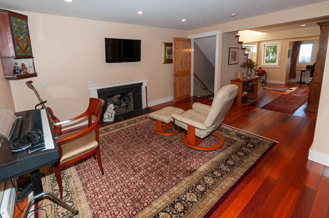 Spacious living room with hardwood floors, a fireplace, and a large area rug, perfect for relaxation. - 2128 Grand Blvd, North Vancouver