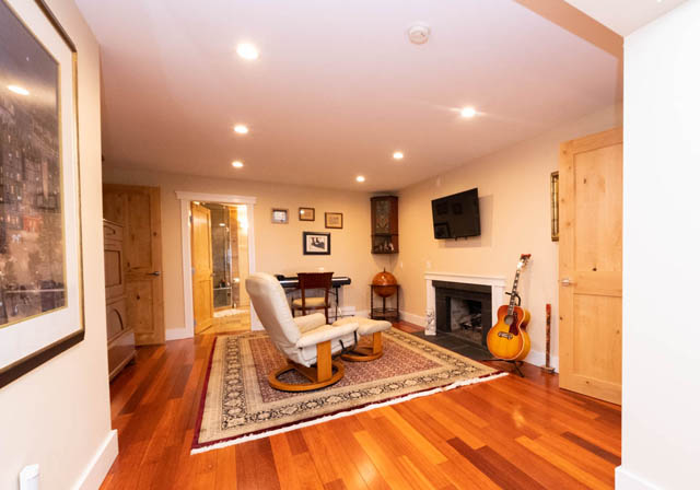 Living room with rich hardwood floors and a stone fireplace. - 2128 Grand Blvd, North Vancouver