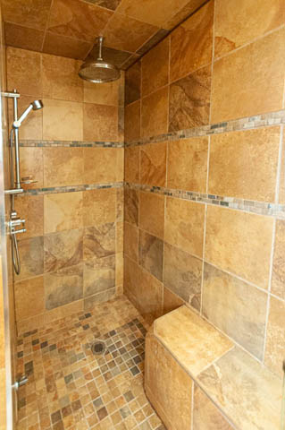 Spacious bathroom with mosaic tile shower, rainfall showerhead, and built-in bench. - 2128 Grand Blvd, North Vancouver