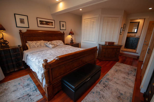 Spacious bedroom with hardwood floors, a large bed, and a walk-in closet. - 2128 Grand Blvd, North Vancouver