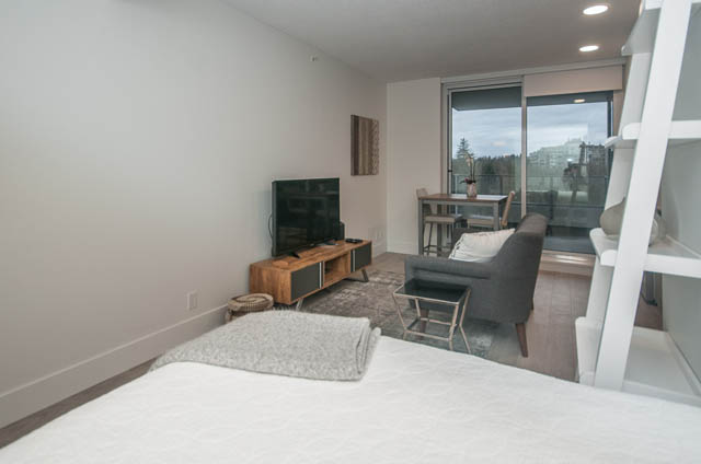 Bright living room with hardwood floors, city view, and modern furnishings. - 907 - 680 Seylynn Crescent, North Vancouver