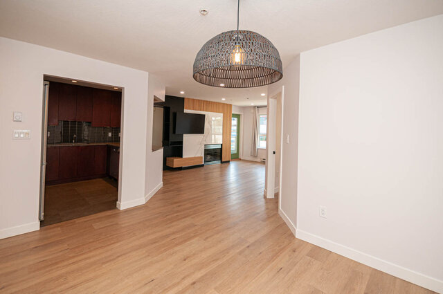 Open-concept living space with hardwood floors, modern lighting, and a view of the city. - 313 - 108 West Esplanade Ave, North Vancouver