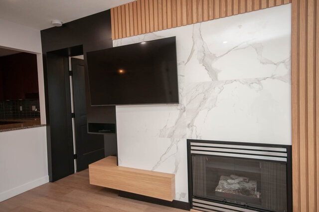 Modern living room with sleek marble fireplace and floating TV unit, featuring hardwood floors and a stylish wood accent...