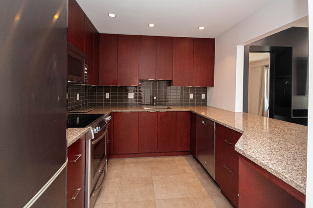 Modern kitchen with granite countertops and red cabinets, featuring a sleek design and ample counter space.