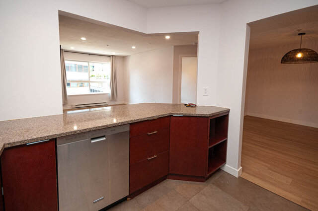 Bright kitchen with granite countertops and hardwood floors, showcasing a modern design. - 313 - 108 West Esplanade Ave, North Vancouver