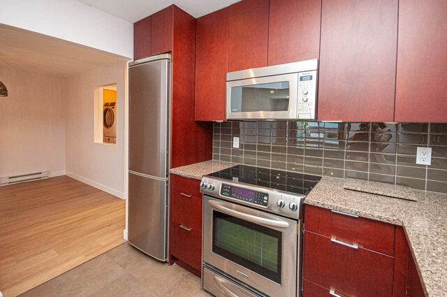 Bright kitchen with granite countertops, stainless steel appliances, and hardwood floors. - 313 - 108 West Esplanade Ave, North Vancouver