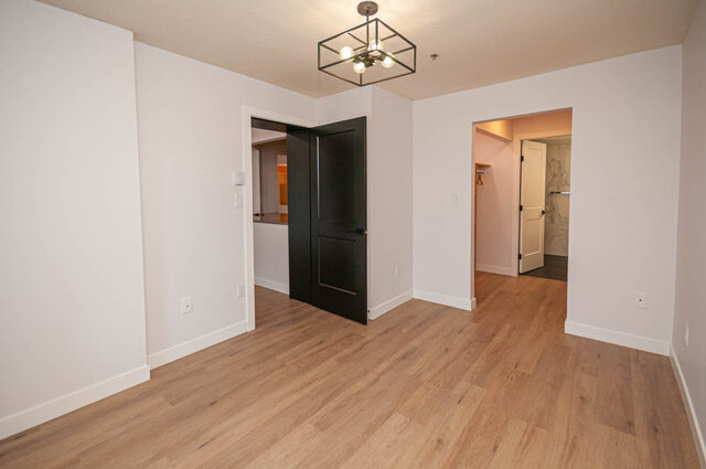 Spacious living room with hardwood floors and a modern chandelier. - 313 - 108 West Esplanade Ave, North Vancouver