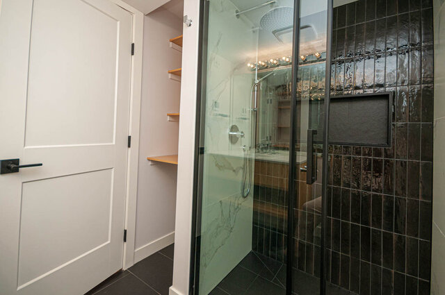 Spacious bathroom with modern glass shower and sleek black tile accents. - 313 - 108 West Esplanade Ave, North Vancouver