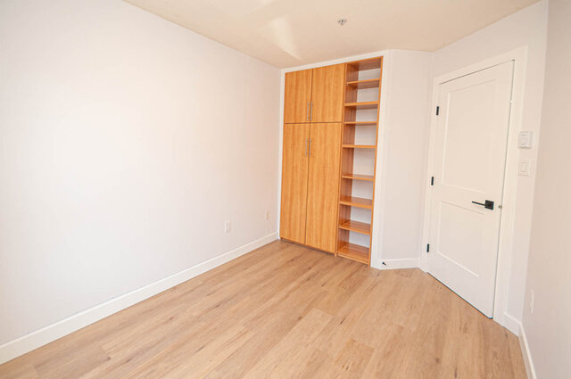 Spacious bedroom with wooden floors and built-in storage. - 313 - 108 West Esplanade Ave, North Vancouver