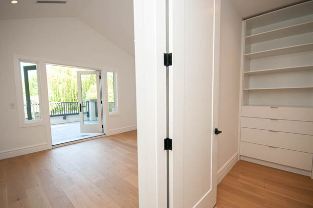 Spacious bedroom with light hardwood floors and built-in closet shelves near French doors. - 5909 Athlone Street, Vancouver West Side