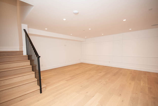 Spacious living area with light wood hardwood floors and black metal staircase railing. - 5909 Athlone Street, Vancouver West Side