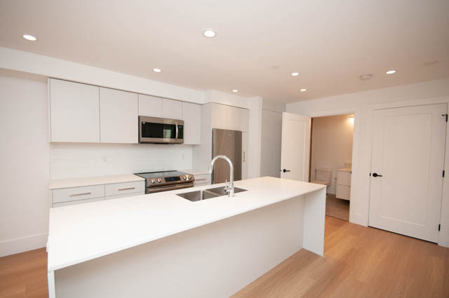 Bright kitchen with white quartz countertops and warm hardwood floors. - 5909 Athlone Street, Vancouver West Side
