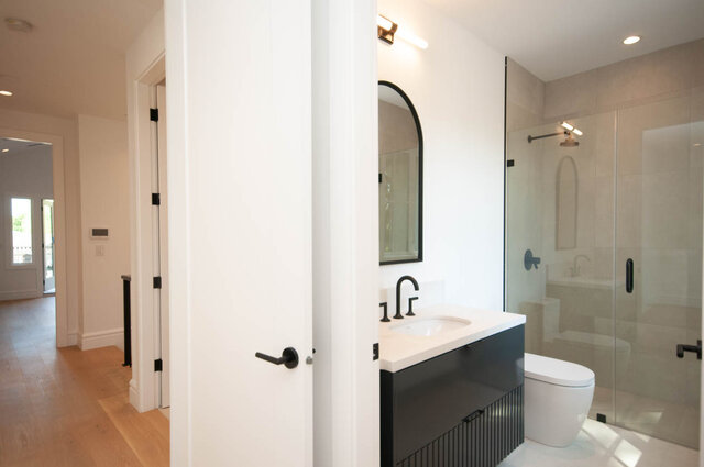 Modern bathroom with white walls, black fixtures, and a glass shower. - Upper - 5909 Athlone St, Vancouver West Side