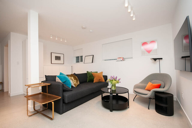 Modern living room with a curved sofa, colorful cushions, and a sleek coffee table. - 2 - 563 Union Street, Vancouver East Side