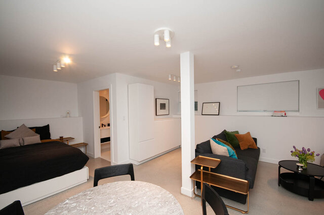 Spacious living room with modern furniture, white walls, and a whiteboard, perfect for shared living. - 2 - 563 Union Street, Vancouver East Side