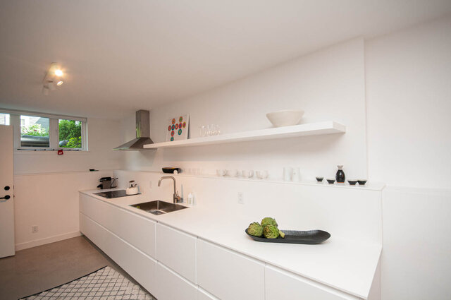 Bright kitchen with white cabinets, modern shelves, and a sleek countertop. - 2 - 563 Union Street, Vancouver East Side
