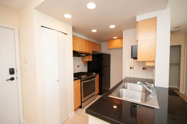 Bright kitchen with black countertops and wooden cabinets, modern design. - 1105 - 198 Aquarius Mews, Vancouver Downtown