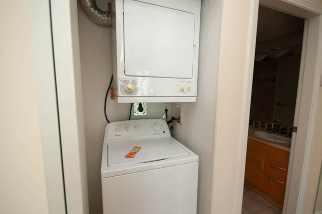 Bright laundry room with white appliances and wooden cabinets. - 1105 - 198 Aquarius Mews, Vancouver Downtown