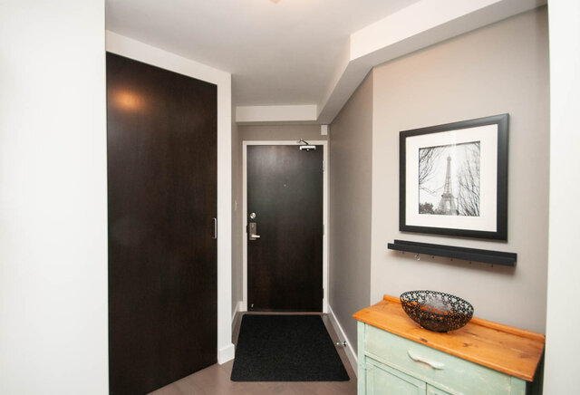 Condo entryway with dark wood doors, gray walls, and a mint cabinet with a wooden countertop and metal bowl. - 1006-4165 Maywood Street, Burnaby