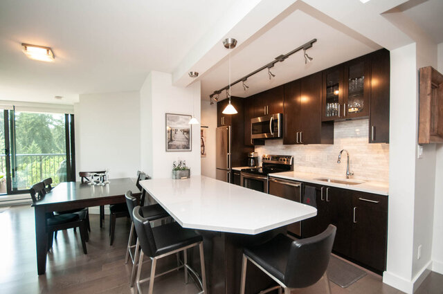 Modern kitchen with dark espresso cabinets, white quartz island, and stainless appliances. - 1006-4165 Maywood Street, Burnaby