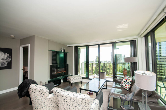 Furnished living room with hardwood floors and floor-to-ceiling windows opening to a balcony with city views. - 1006-4165 Maywood Street, Burnaby