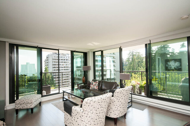Furnished living room with floor-to-ceiling windows, hardwood floors, and a view of trees and high-rises. - 1006-4165 Maywood Street, Burnaby