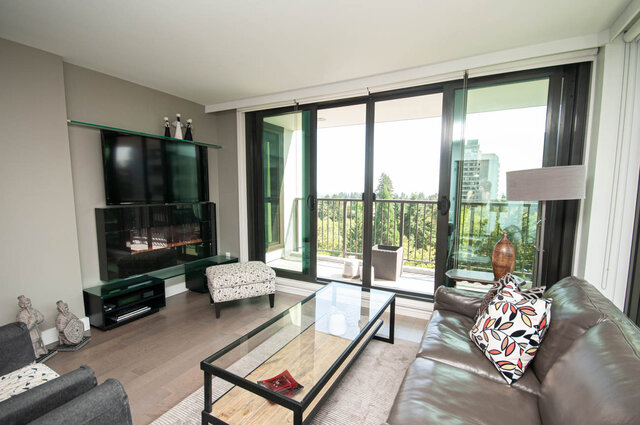 Furnished living room with leather sofa, glass coffee table, and sliding doors to a balcony with green views. - 1006-4165 Maywood Street, Burnaby
