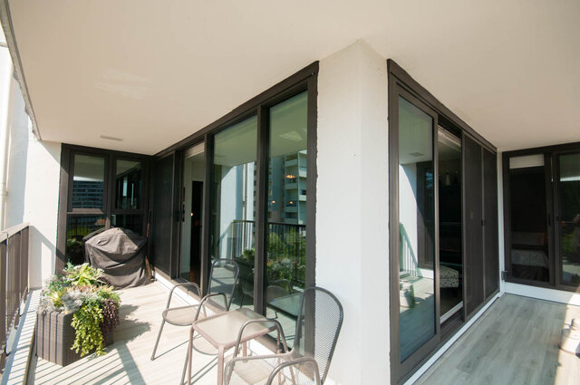 Spacious balcony with light wood-look flooring, dark-framed sliding glass doors, and a small outdoor dining set. - 1006-4165 Maywood Street, Burnaby