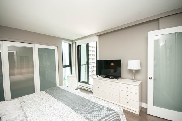 Bedroom with hardwood floors, frosted glass closet doors, and a city view through the windows. - 1006-4165 Maywood Street, Burnaby