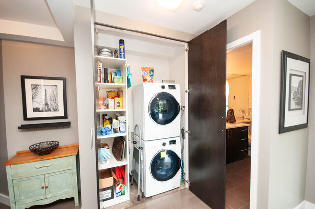 Laundry closet with stacked washer and dryer beside stocked built-in shelving. - 1006-4165 Maywood Street, Burnaby