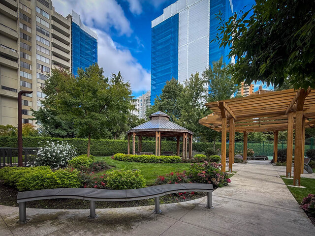 Courtyard garden with wooden pergola, gazebo, and manicured hedges against a city skyline. - 1006-4165 Maywood Street, Burnaby