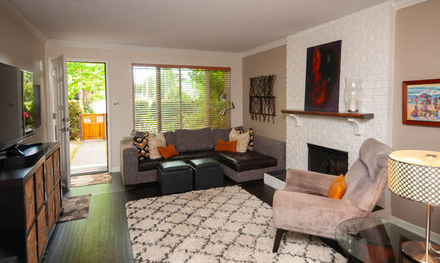 Furnished living room with hardwood floors, large windows, and a cozy fireplace. - 2077 W 13th Ave, Vancouver West Side