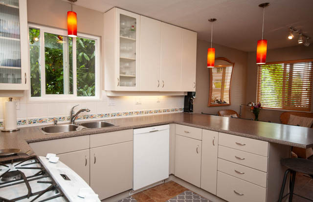 Bright kitchen with white cabinets, granite countertops, and a window with a view of greenery. - 2077 W 13th Ave, Vancouver West Side