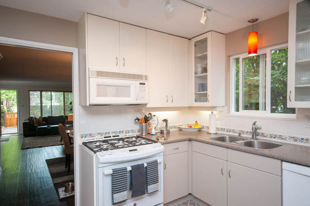 Bright kitchen with white cabinets, stainless steel sink, and hardwood floors. - 2077 W 13th Ave, Vancouver West Side