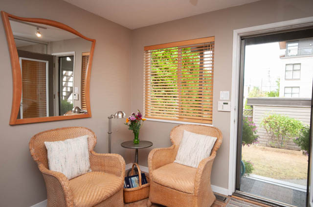 Furnished living room with wicker chairs, large mirror, and city view. - 2077 W 13th Ave, Vancouver West Side
