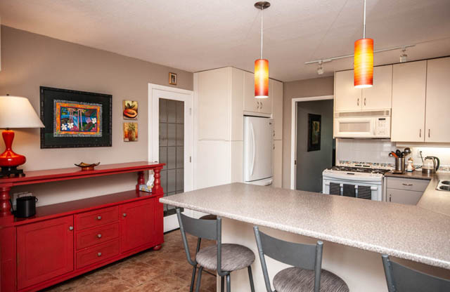 Bright kitchen with red cabinets, granite countertops, and modern pendant lights. - 2077 W 13th Ave, Vancouver West Side