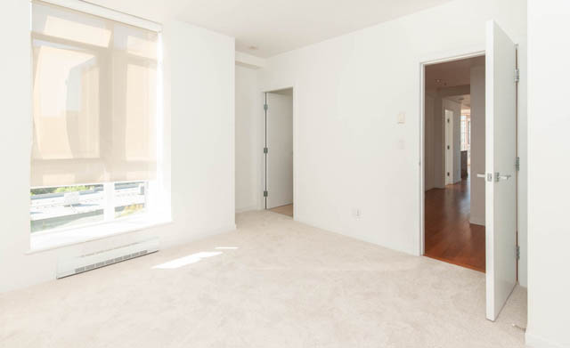 Bright living room with white walls, hardwood floors, and a large window. - 903 - 5989 Walter Gage Rd, Vancouver West Side