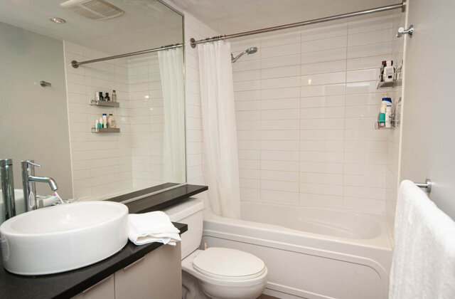 Modern bathroom with white tiles and a sleek black countertop. - 1601 - 788 Hamilton Street, Vancouver Downtown