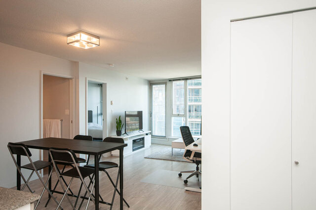 Modern open-concept living space with hardwood floors, a sleek kitchen counter, and a city view through large windows.