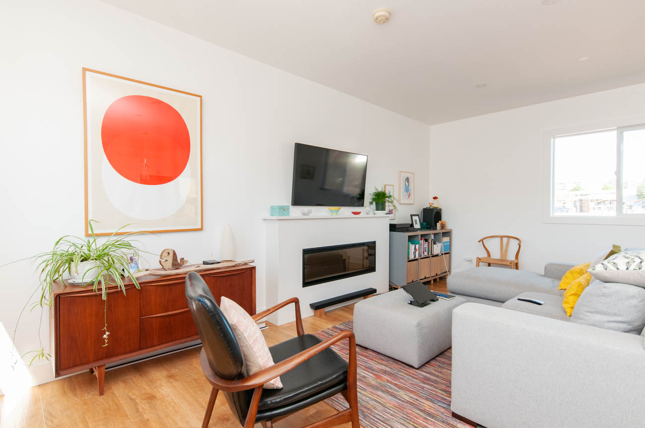 Bright living room with modern furniture, a large red and white abstract painting, and a fireplace. - 415 West Esplanade EFH-10, North Vancouver